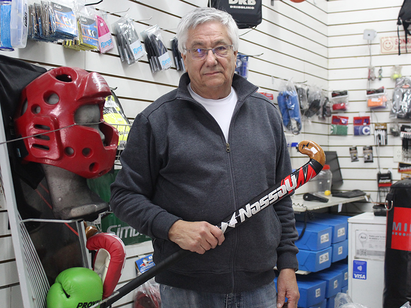 Oscar Domenech sosteniendo un palo de hockey en su mano derecha