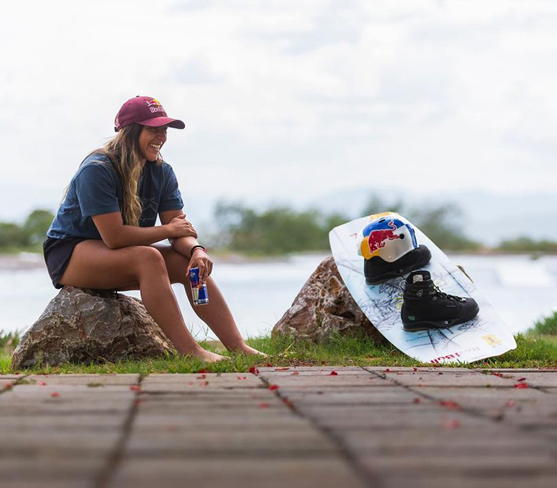 eugenia de armas con su tabla Red Bull, sentada en un tronco